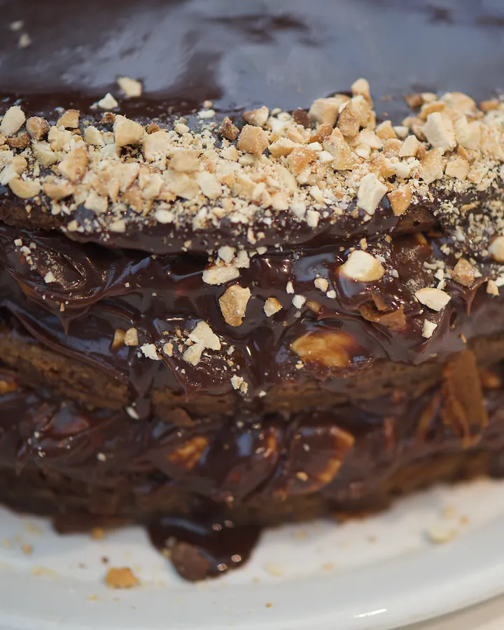 Whole layered chocolate cashew nut cake topped with chopped cashews