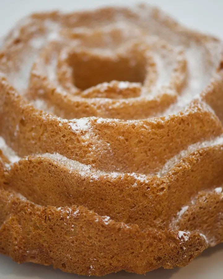 Whole vanilla bundt cake in a rose shape, dusted with icing sugar
